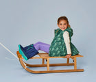 Girl riding snow sled wearing Ten Little Snow Boots in Navy and Teal. Available at www.tenlittle.com