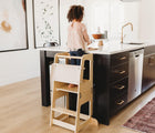 Child standing on the Convertible Kitchen Tower with safety net. Available from www.tenlittle.com