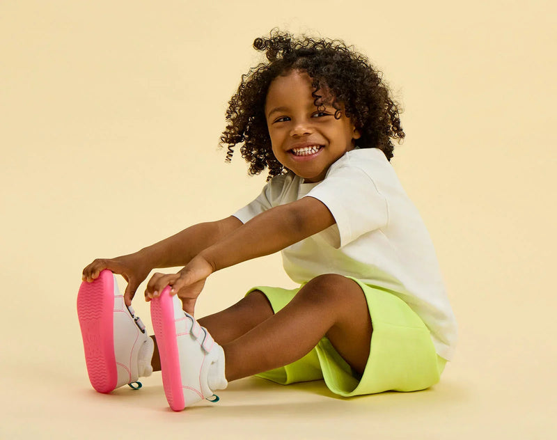 Child sitting wearing Ten Little Everyday Original - Neon Glow - Neon Pink. Available at www.tenlittle.com