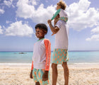 Boy with dad at beach wearing Snapper Rock UPF 50+ Top & Swim Shorts - Lobsters. Available at www.tenlittle.com