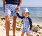 Boy at beach with dad wearing Snapper Rock Long Sleeve UPF 50+ Swimsuit - Turtle Break. Available at www.tenlittle.com