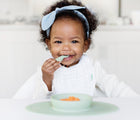 Baby eating in Ezpz First Food Set Sage.  Available at www.tenlittle.com