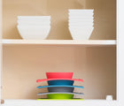 ezpz Mini Bowl in blue in cabinet stacked with other ezpz Mini Bowl colors. Available from tenlittle.com