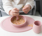 Baby Eating ezpz Tiny Bowl in Pink with food inside. Available at www.tenlittle.com