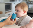 Baby drinking out of ezpz Tiny Cup in blue. Available from tenlittle.com