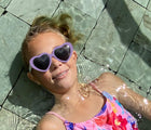 Girl in pool wearing Ten Little Roshambo Heart Sunglasses - Lilac. Available at www.tenlittle.com