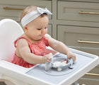 Child sitting in highchair eating from the ezpz Tiny Placement in pewter. Available from tenlittle.com