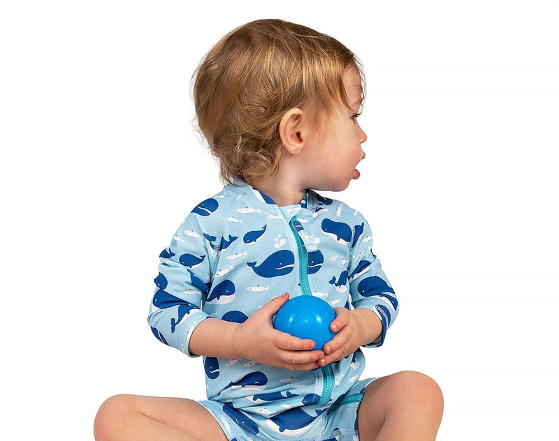 Child wearing Jan & Jul Long Sleeve UV Sun Suit in Whale, holding a blue ball. Available from tenlittle.com