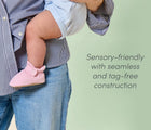 Mom holding baby wearing sensory-friendly Ten Little Everyday Baby Booties with seamless and tag-free construction - Soft Pink. Available at www.tenlittle.com