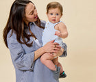 Mom holding baby wearing Ten Little Everyday Baby Booties - Heather Gray. Available at www.tenlittle.com