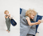 Child  lying and carrying the Bloomere Portable Bedding Set - Navy Checkered - Available at www.tenlittle.com