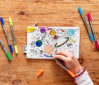 Child coloring in eatsleepdoodle Space Pencil Case Color and Learn. Available from www.tenlittle.com.