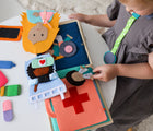 Child playing with Educating Amy Medic Quiet Book. Available from www.tenlittle.com.