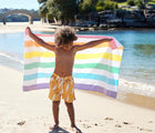 Boy using Dock & Bay Unicorn Wave Quick Dry Beach Towel. Available from www.tenlittle.com.