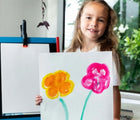 Child holding flower painting made with Honeysticks Natural Watercolor Paint Set. Available at www.tenlittle.com