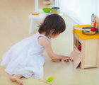 Kid playing at the oven of Plan Toys Compact Kitchen Set - Available at www.tenlittle.com