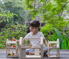 Girl playing Plan Toys Slide N Go Dollhouse & Accessories -Available at www.tenlittle.com