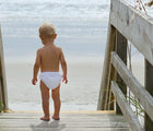 Child at the beach wearing Green Sprouts Eco Snap Swim Diaper. Available from www.tenlittle.com.
