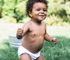 Child in the backyard wearing Green Sprouts Eco Snap Swim Diaper. Available from www.tenlittle.com.