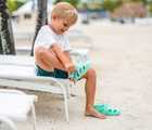 Child at beach wearing Ten Little Splash Sandals in Aqua Mint. Available from www.tenlittle.com