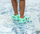 Child standing in water area wearing Ten Little's Splash Sandals in Aqua Mint. Available from www.tenlittle.com
