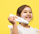 Child holding the Sqween Sunscreen Brush. Available from www.tenlittle.com