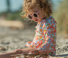 Child on the beach in the Snapper Rock One piece UPF 50+ Swimsuit - Hawaiian Luau. Available from www.tenlittle.com