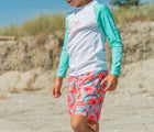 Child outside in the Snapper Rock One piece UPF 50+ Swim Shorts -Geo Melon. Available from www.tenlittle.com