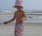 Child at the beach wearing the Snapper Rock One piece UPF 50+ Swim Shorts - Hawaiian Luau. Available from www.tenlittle.com