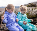 Two Girls at the lake sitting and wearing Girl Playing sand and wearing Therm SplashMagic Eco Fleece Rain Jacket - Aqua & Purple - Available at www.tenlittle.com
