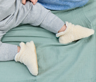 Child sitting wearing Ten Little Sherpa Baby Booties. Available at www.tenlittle.com