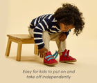Child sitting wearing Ten Little Furry High Tops, easy for kids to put on and take off independently - Lava Red. Available at www.tenlittle.com