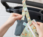 Woman clipping Bumkins Wet/Dry Bag - Wander to stroller. Available from www.tenlittle.com