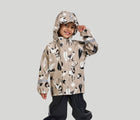 Child with hood on wearing Reima Waterproof Rain Jacket - Vesi - Earthy Beige. Available at www.tenlittle.com