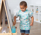 Child wearing the Bumkins Short-Sleeved Art Smock - Dinosaurs. Available from www.tenlittle.com