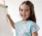 Close up of child wearing the Bumkins Short-Sleeved Art Smock - Rainbows. Available from www.tenlittle.com