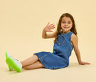 Child sitting and waving wearing Ten Little Everyday Original - Neon Glow - Neon Green. Available at www.tenlittle.com