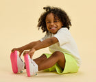 Child sitting wearing Ten Little Everyday Original - Neon Glow - Neon Pink. Available at www.tenlittle.com