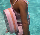 Girl in pool wearing Sunnylife Bubble Back Float - Cherry. Available at www.tenlittle.com