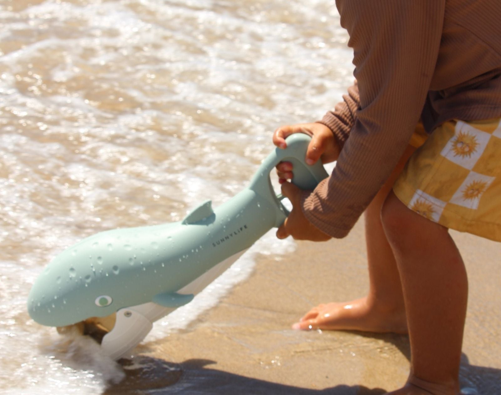 Child scooping sand with Sunnylife Sand Claw - Whale. Available at www.tenlittle.com