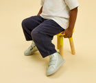 Child sitting wearing Ten Little Everyday High Top - Moondust Silver. Available at www.tenlittle.com