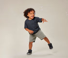 Boy playing with bubbles wearing Ten Little Mid Top Sneakers - Matte Black. Available from www.tenlittle.com