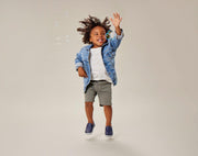 Child playing with bubbles wearing Ten Little Slip-On Sneakers - Navy Blue. Available at www.tenlittle.com