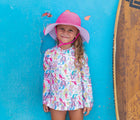 Child wearing Flap Happy UPF 50+ Swim Hat - Pink. Available from www.tenlittle.com