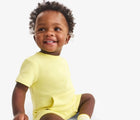 Baby sitting wearing Primary Baby French Terry Romper - Buttercup. Available at www.tenlittle.com