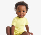 Baby sitting wearing Primary Baby French Terry Romper - Buttercup. Available at www.tenlittle.com