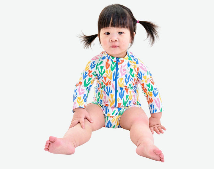 Baby wearing Primary Baby One-Piece Rash Guard - White / Tulips. Available at www.tenlittle.com