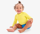 Baby sitting wearing Primary Baby Rash Guard - Banana. Available at www.tenlittle.com