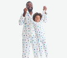 Child with adult wearing Primary Adult Holiday PJ Set - Rainbow Village - Ivory Rainbow Winter Village. Available at www.tenlittle.com