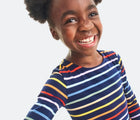 Child wearing Primary Long Sleeve Pocket Dress - Rainbow Stripe - Navy / Rainbow Stripe. Available at www.tenlittle.com